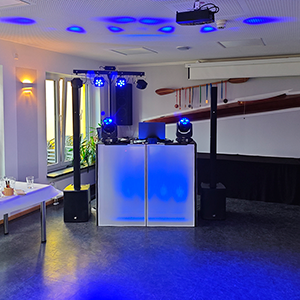 DJ Greußen Setup mit moderner Licht- und Tontechnik bei einer Indoor-Veranstaltung. DJ-Pult in stilvoller LED-Beleuchtung, professionelle Lautsprecher und Lichteffekte von DJ Greußen erzeugen stimmungsvolles Ambiente für eine Feier. Typisches DJ Greußen Equipment für Hochzeiten, Geburtstage und Events.